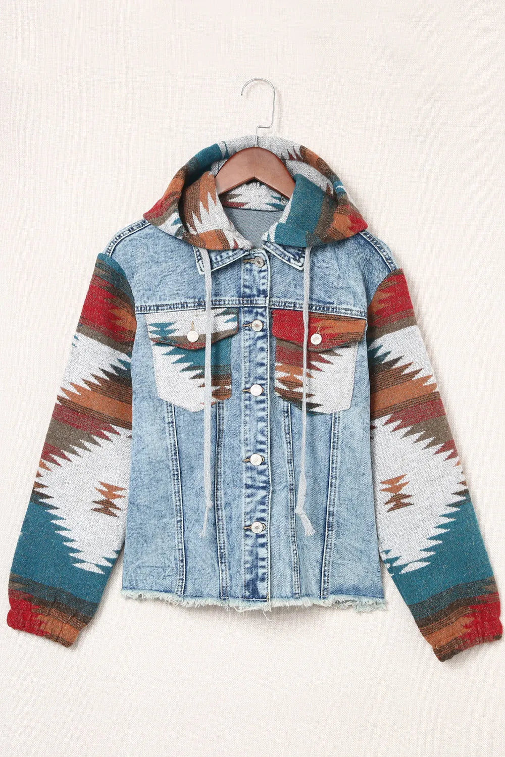 Drawstring hooded denim jacket with colorful patterned sleeves, front pockets, and button closure.