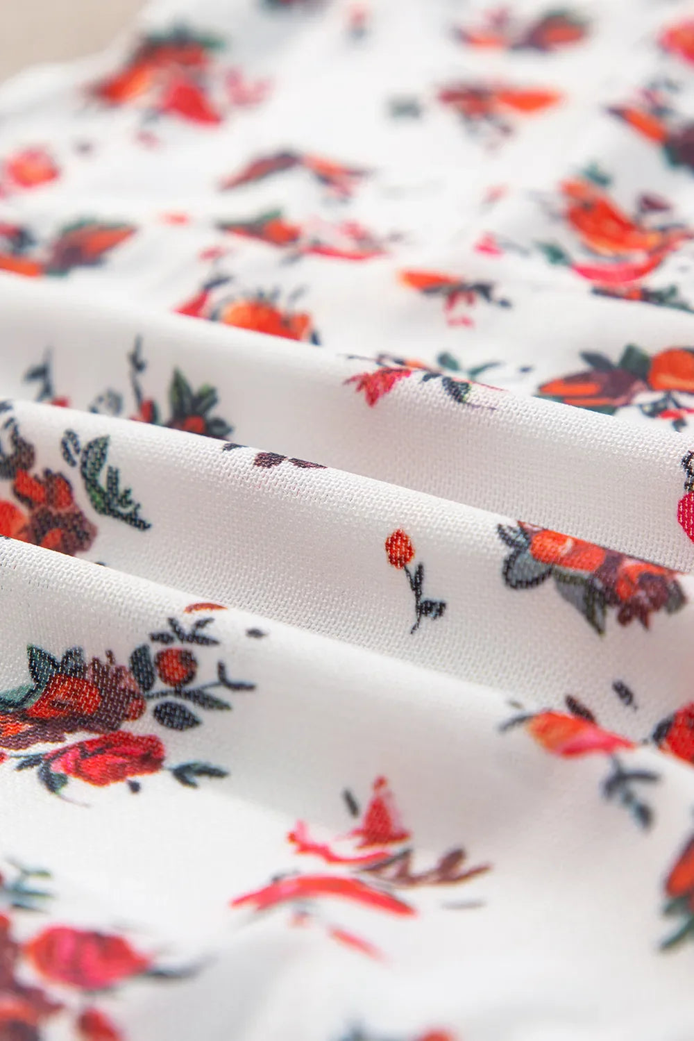 Floral frilled trim fabric detail, highlighting vibrant red and orange flower pattern on white background.