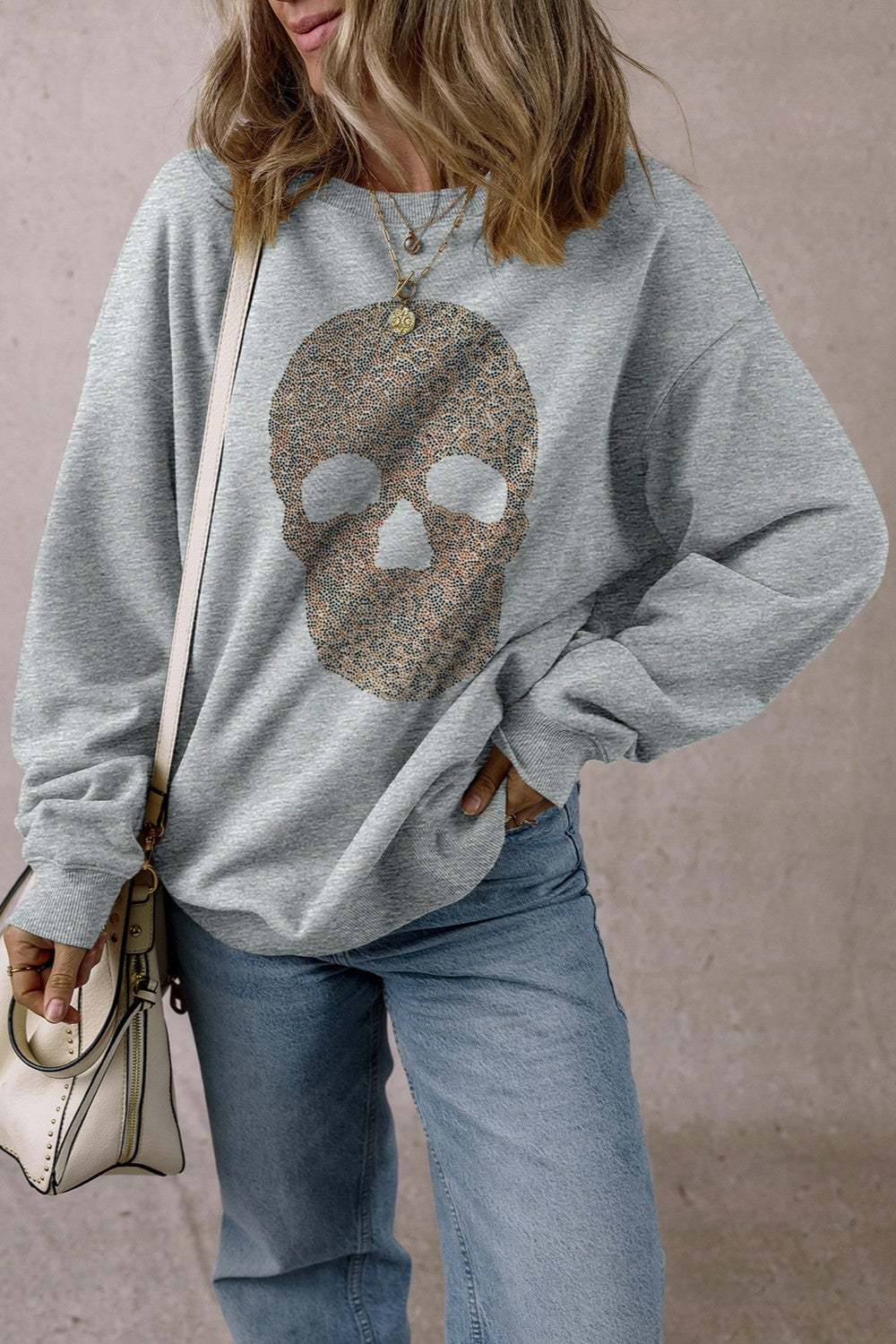 Skull round neck long sleeve sweatshirt with rhinestone design, worn by a person with a casual outfit.
