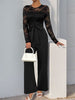 Perfee Lace Round Neck Long Sleeve Jumpsuit in black, featuring semi-sheer lace and tied waist, paired with a white handbag and heels.