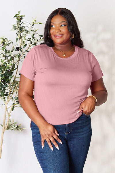 Basic Bae Full Size Round Neck Short Sleeve T-Shirt in pink, worn by a model paired with jeans, featuring a comfortable fit and slightly stretchy material.