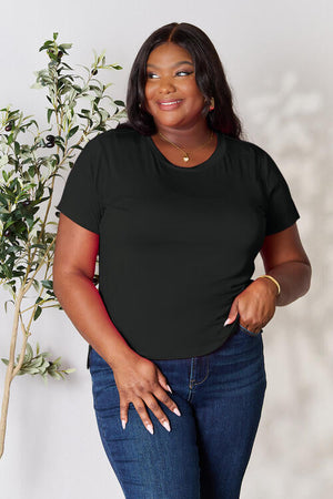 Basic Bae Full Size Round Neck Short Sleeve T-Shirt worn by a woman standing in front of a plant.
