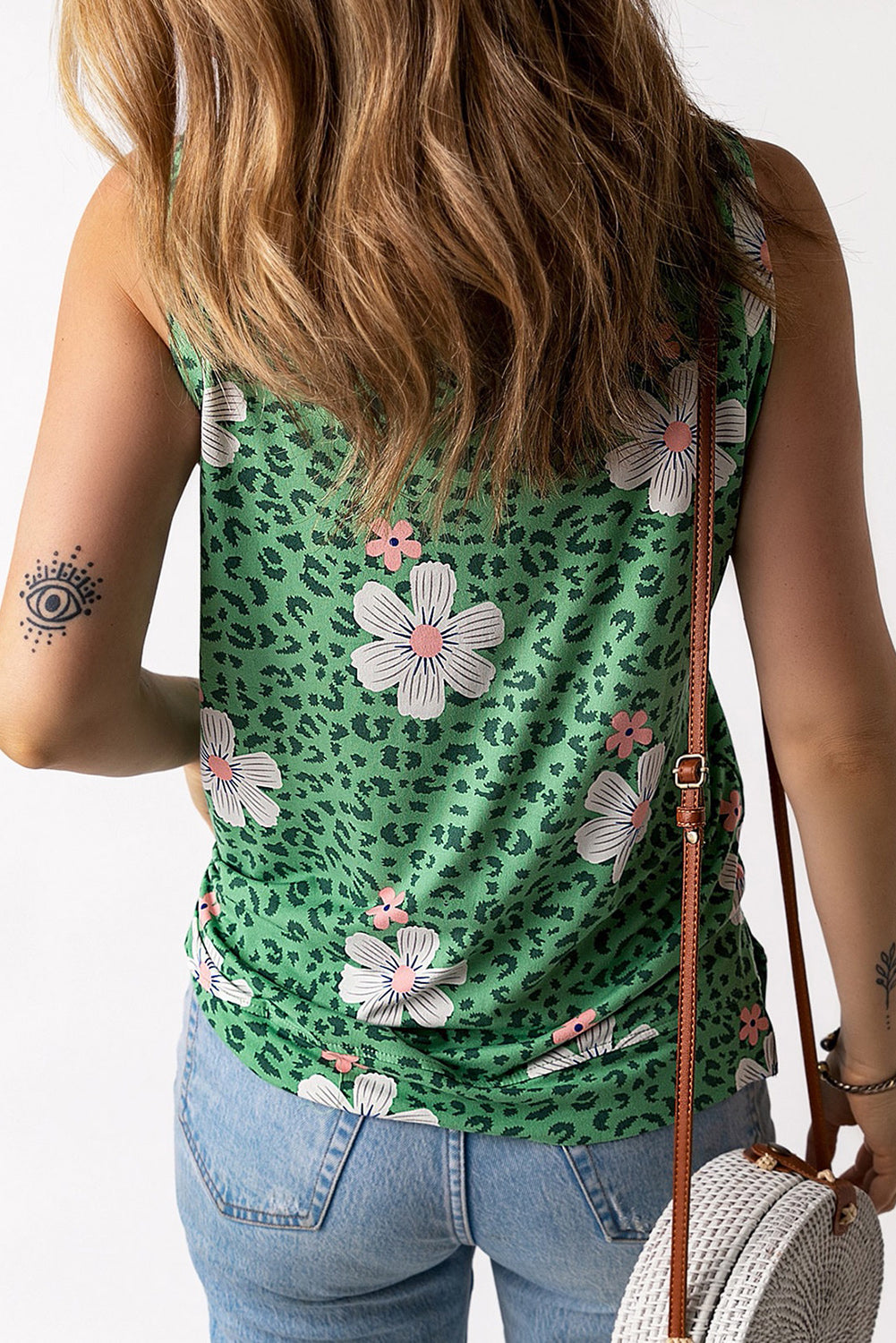 Sleeveless round neck tank with floral and animal print featuring a side slit, worn casually with jeans.