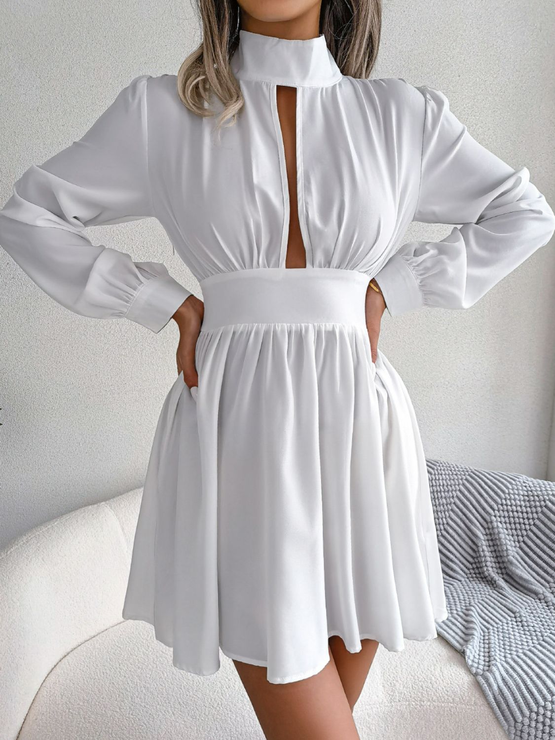 Cutout turtleneck A-line mini dress with long sleeves and keyhole neckline in studio setting.