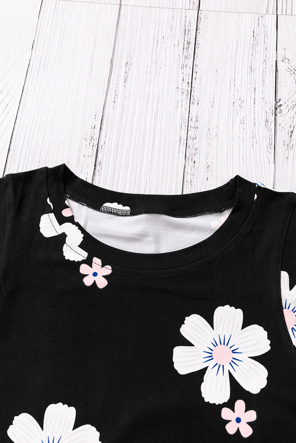 Printed side slit round neck tank with floral pattern on black fabric, sleeveless design.
